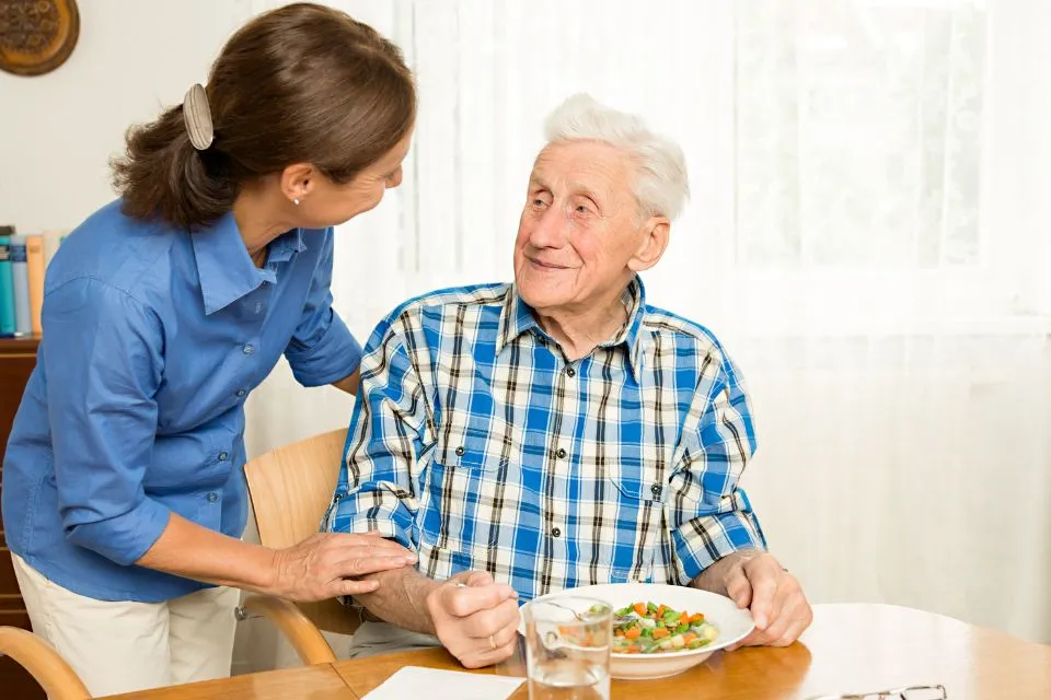 Carer giving senior man lunch